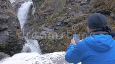 一个男人在山上拍摄一个美丽的瀑布，在智能手机上。 过着活跃有<strong>趣</strong>的<strong>生活</strong>